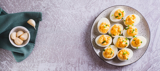Boiled eggs stuffed with yolk, cheese, garlic and mayonnaise on a plate top view web banner