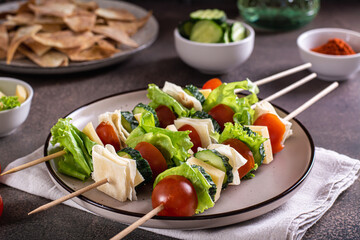 Snack on skewers of tomatoes, cucumber, cheese, pita bread and lettuce on a plate