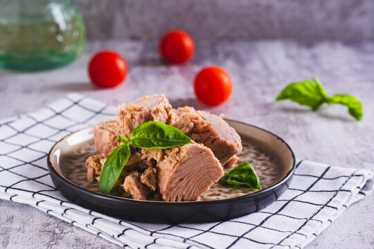 Pieces of canned tuna and basil leaves on a plate