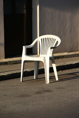 Fototapeta na wymiar A white plastic chair on the street