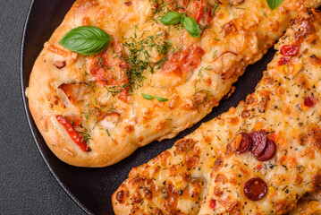 Delicious oven fresh flatbread pizza with cheese, tomatoes, sausage, salt and spices