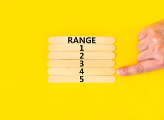 Time to range 4 symbol. Concept word Range 1 2 3 4 5 on wooden sticks. Businessman hand. Beautiful yellow table yellow background. Business planning and time to range 4 concept. Copy space.