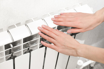 female hands touch the heating radiator, checking its warmth