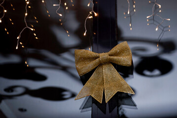 New Year decoration . Garland and golden big bow on the wall.