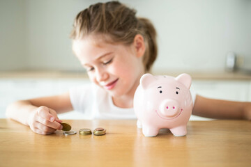 Caucasian child girl counting some coins with a pink piggy bank. Saving money for kids concept.