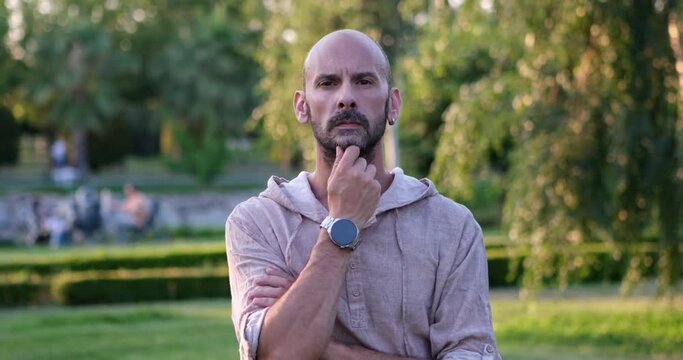 A man looks at the camera and makes gestures and facial expressions, placing her hand on her chin, as if she is attentively listening to someone and reacting to their remarks