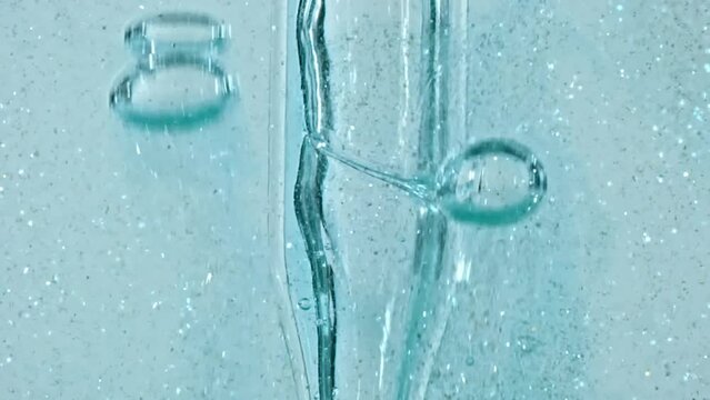 Transparent Cosmetic Gel Fluid With Molecule Bubbles and Oil Flowing in Glass Tube with Clear Liquid on White Background. Macro shot. Production Close-up. Slow Motion. High quality FullHD footage