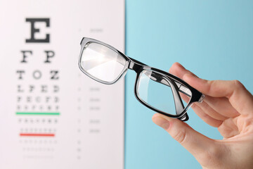vision correction glasses in hand against the background of a vision test table with space for text