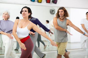 Enthusiastic young Hispanic woman attending group choreography class, learning modern dynamic dances