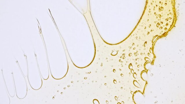 Transparent cosmetic gel fluid with molecule bubbles oil distribution on a white background. Macro Shot of Natural Organic Cosmetics, Medicine. Production Close-up. Slow Motion. High quality 4k