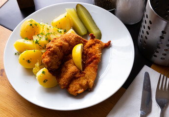 Appetizing fried chicken cutlet breaded with Parmesan served with boiled potatoes, greens and...
