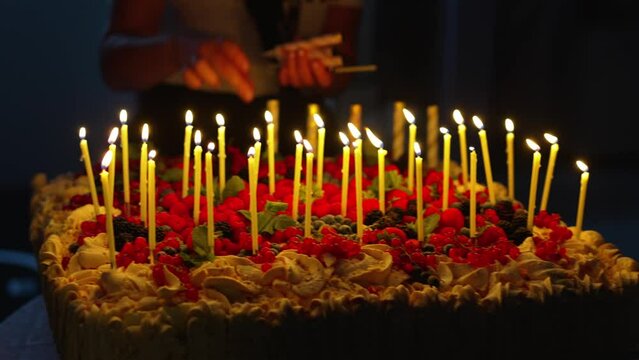 hands collecting a lot of candles on a large birthday cake