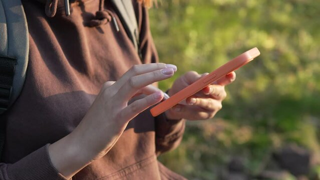 close up hands of woman use smartphone mobile phone outdoor in nature