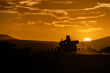 Motorcyclist silhouette at sunset by motorcycle by Patagonian route.