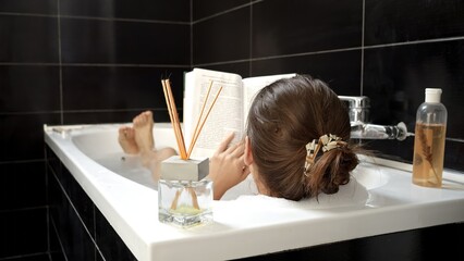 A woman taking a relaxing bath while reading a book. Importance of personal enrichment and mental...