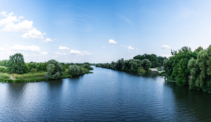 Panorama rzeki Odry w tle lekko pochmurna pogoda, błękit nieba zieleń przy brzegu, pora letnia, Odra w odcinku województwa Opolskiego - obrazy, fototapety, plakaty