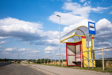 Żółto niebieski przystanek autobusowy stojący na odludziu po za obszarami wiejskimi o letniej porze w zachodniej Polsce - obrazy, fototapety, plakaty