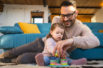 Fototapeta premium Adult caucasian man father play with daughter two years old girl