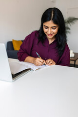 Vertical shot of young adult indian woman studying online from home. Education lifestyle and...