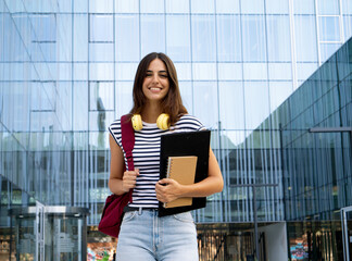Portrait of student girl with folder in a campus looking at camera smiling. Happy student