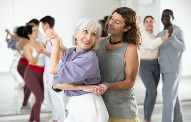 Fototapeta premium Adult couples of dancers, engaged in a dance studio, studying salsa in lesson
