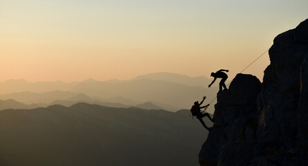 Silhouette of Two Climbers Climbing a Challenging Rock