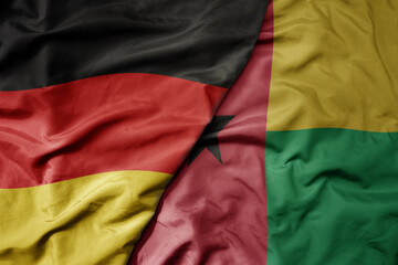big waving realistic national colorful flag of germany and national flag of guinea bissau .