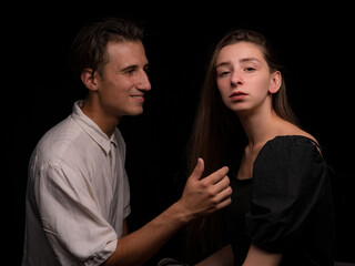 young couple white brunette man and white brunette woman with long hair on a dark background