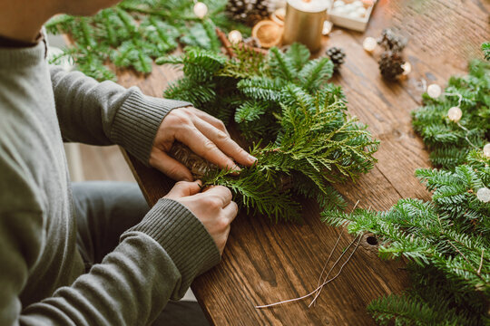 The hands of a male florist makes a New Year's drenching from fresh spruce branches, cones and dried fruits. New Year's master class