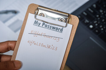 Man holding note his new more secure password containing alphanumeric characters for data protection. Selective focus. 