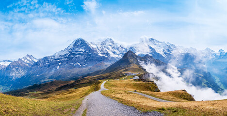 Autumn in Swiss Alps. Hiking trail on top of Mannlichen near Wengen and Lauterbrunnen, Switzerland. Mountain range with peaks Eiger, Monch, Jungfraujoch and Jungfrau in clouds. Grindelwald valley © Julia Lavrinenko