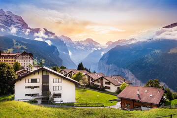 Fototapeta na wymiar Wengen town in Switzerland at sunset. View over Swiss Alps near Lauterbrunnen valley. Typical Swiss houses in Wengen. Mountain peaks of Eiger and Jungfrau covered with snow and clouds
