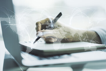 Double exposure of abstract digital world map with connections and hand writing in notebook on background with laptop, research and strategy concept