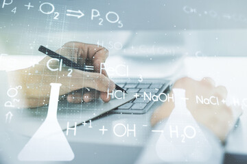 Double exposure of creative chemistry concept with hand writing in notebook on background with laptop, research and development concept