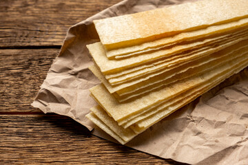 Long potato chips on old wooden table.