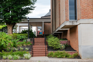 Brick steps leading to a brick house among flowers and plants.