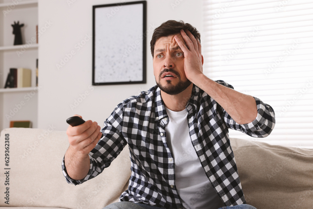 Wall mural emotional man with remote controller watching tv at home