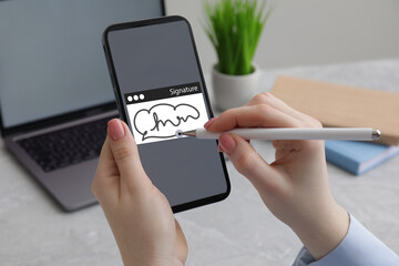 Electronic signature. Woman using stylus and mobile phone at table, closeup