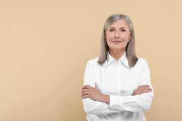 Portrait of beautiful senior woman on beige background. Space for text