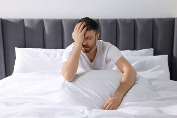 Sleepy man with blanket on soft bed at home in morning
