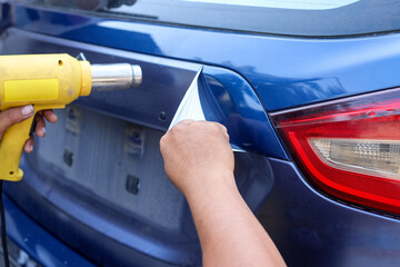 Car wrapping specialists removing vinyl foil or film from a car