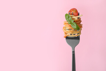 Tasty pasta with tomato sauce and basil on fork against pink background, space for text