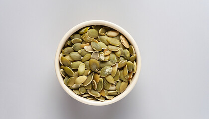 bowl with pumpkin seeds on white background, top view horizontal