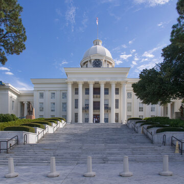 The Alabama State Capitol in Montgomery, Alabama, USA, is stretching towards a blue sky with small white clouds.