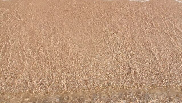 Water splash. Sand, corals. Pure water with reflections sunlight and shadows in slow motion. Water surface texture top view. Sea water wave come to beach. Beach sea sand summer day. High quality 4k 
