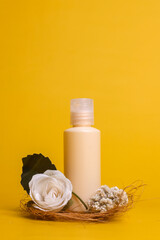 Fototapeta na wymiar Minimalist summer style of showcase for cosmetics product display on yellow background with flowers. Beige bottle cosmetics product with flowers
