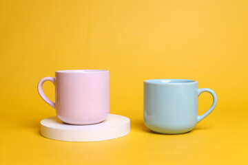 Minimalist style of two pastel ceramic mugs isolated over yellow color with blank space for logo, ad and design