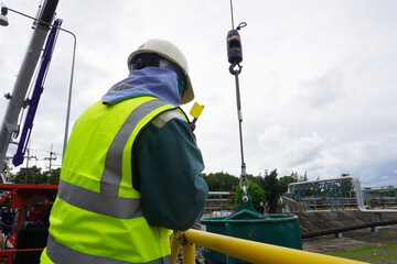 Worker or rigger during lifting deformed bars by using hand signal which meant crane is up in...