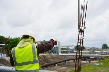 Worker or rigger during lifting deformed bars by using hand signal which meant crane is up in construction chemical site.  