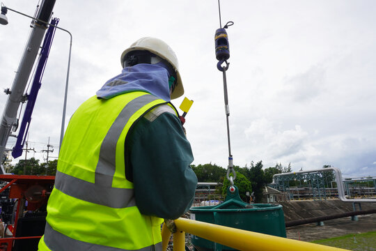Worker or rigger during lifting deformed bars by using hand signal which meant crane is up in construction chemical site.  